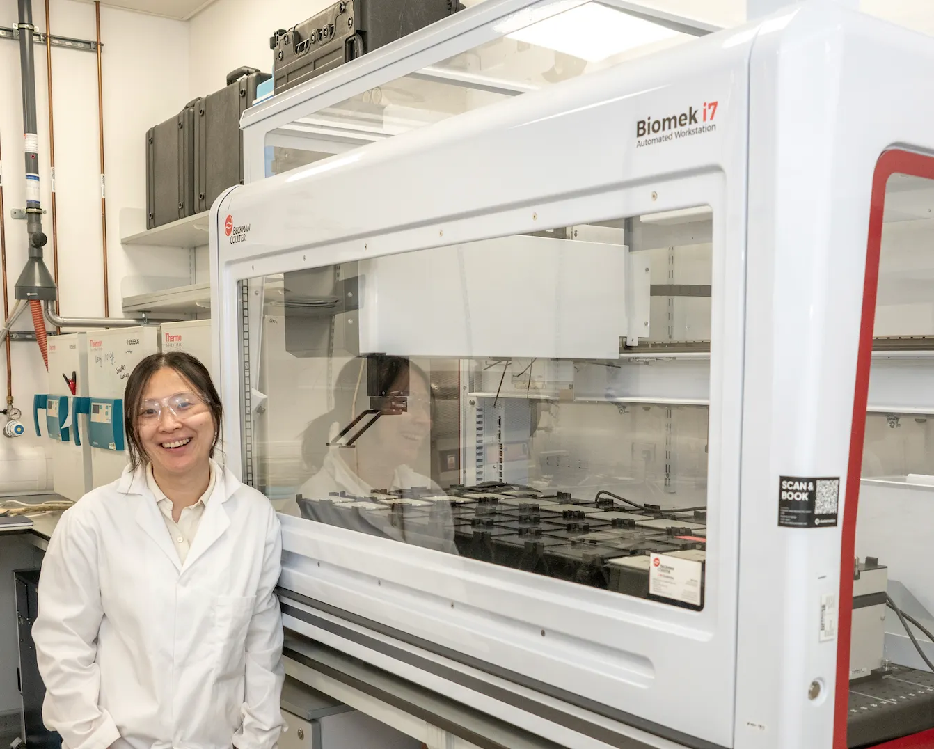 Shijing Sun beside laboratory automation equipment
